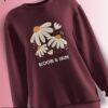 Maroon fleece sweatshirt with a daisy floral design and the phrase 'BLOOM & SHINE' in soft pastel colors.