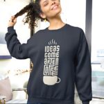 Navy blue fleece sweatshirt with a vintage-style coffee cup typography design and the phrase 'IDEAS COME AFTER COFFEE.'